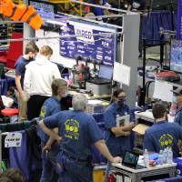 A team stands with their mentors in their pit